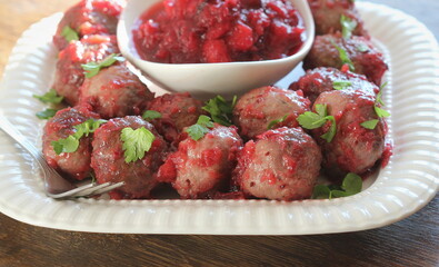 Hot meatballs with cranberry sauce on white plate