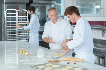 baker instructing apprentice how to knead dough properly