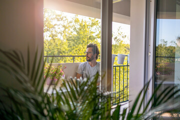 Man drinking coffee on the balcony of his apartment 
