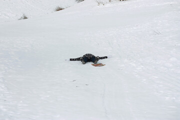 Young woman on a walk in winter. Dressed in winter clothes. Lies in the snow. There is a lot of snow around.