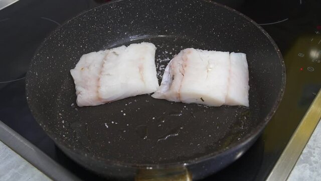 Fillet of sea codfish frying in a frying pan n domestic home kitchen. Appetizing and delicious seafood dish closeup.