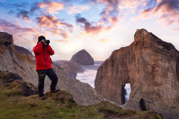 Photographer is taking pictures of the beautiful seaside view on the Oregon Coast. Taken in Cape Kiwanda, Pacific City, during a cloudy winter Sunset.