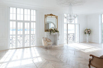 chic white huge spacious hall with a minimum of expensive antique furniture. Baroque interior design with ornament on the walls and parquet on the floor.