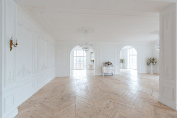 chic white huge spacious hall with a minimum of expensive antique furniture. Baroque interior design with ornament on the walls and parquet on the floor.