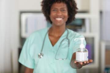 cheerful female nurse holding forwards some hand sanitiser