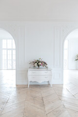 chic white huge spacious hall with a minimum of expensive antique furniture. Baroque interior design with ornament on the walls and parquet on the floor.