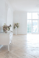 chic white huge spacious hall with a minimum of expensive antique furniture. Baroque interior design with ornament on the walls and parquet on the floor.