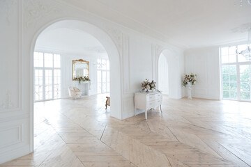 chic white huge spacious hall with a minimum of expensive antique furniture. Baroque interior design with ornament on the walls and parquet on the floor.