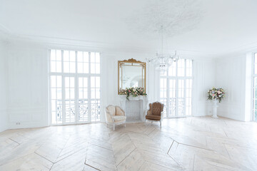 chic white huge spacious hall with a minimum of expensive antique furniture. Baroque interior design with ornament on the walls and parquet on the floor.