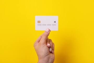 credit card in hand, card with electronic chip over yellow background