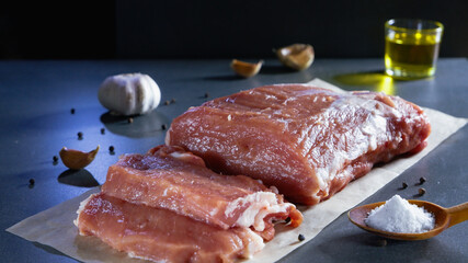 Cooking food. Fresh raw meat cut into steaks with spices and olive oil on a dark background