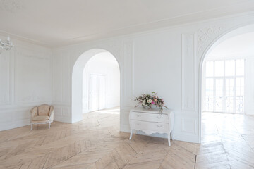 chic white huge spacious hall with a minimum of expensive antique furniture. Baroque interior design with ornament on the walls and parquet on the floor.