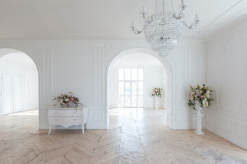 chic white huge spacious hall with a minimum of expensive antique furniture. Baroque interior design with ornament on the walls and parquet on the floor.