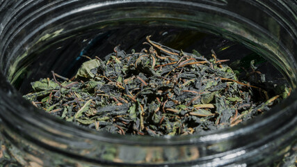Dry leaves of black and green tea keeping in glass jar container top close view.