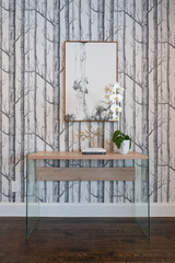 Detail of home entry hall with wood and acrylic side table, potted orchid and tree themed wall covering.