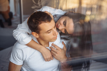 Reflection in glass, in a mirror. Hot couple in love man and woman slowly undress each other before...