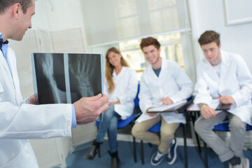 Doctor holding xrays before class of students