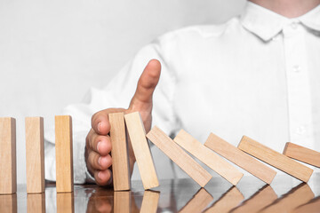 Close-up Of A Human Hand Stopping Wooden Blocks From Falling On Table. The man's hand holds the...