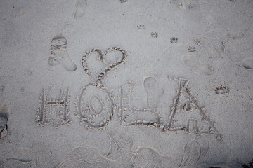 The word hi written in spanish in the sand of the beach with a heart, hola © Banana Images