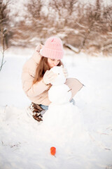 beautiful girl sculpts a snowman