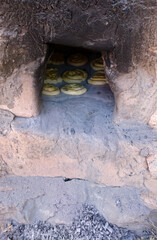 Obraz premium Ashes in front of a traditional wood oven made of a special kind of stone. Homemade breads are baked in the wood-fired oven. Selective focus.
