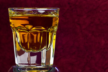 On a brown blurred background on the left side of a glass with whiskey close-up. On the right is a place for an inscription