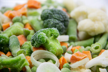 Frozen vegetables: cauliflower, green peas, leeks, broccoli, carrots, green beans on a white plate.