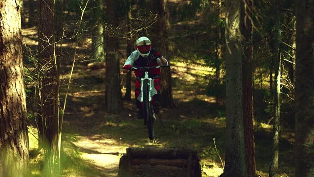 A man jumping in air with mtb in a forest in super slow motion, front view