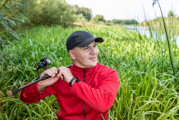 Portrait of a  fisherman with a spinning. Guy with a fishing rod outdoors.