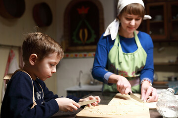 Mother and son cutting dough into strips for cooking chak-chak