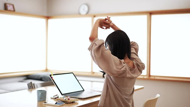 在宅での仕事中に深呼吸する女性
