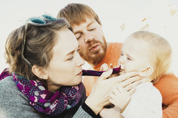 Mom wiping baby lips after eating. Family couple and toddler sitting in outdoor cafe. Leisure time or coffee break concept