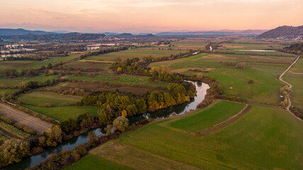 Fototapeta na wymiar Spectacular aerial panorama of river flowing through fields at sunset.