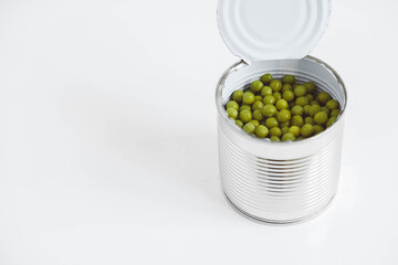 Canned green sweet peas in an open aluminum metal can on a white table. Copy, empty space for text