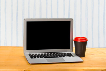 Fototapeta premium mocap Laptop with blank screen for product display and coffee on a wooden table.