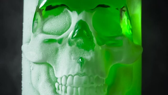 Glass Skull in Frost. A glass vessel with a bright, rich emerald-green content in the form of a glass skull, cooled by liquid evaporating nitrogen