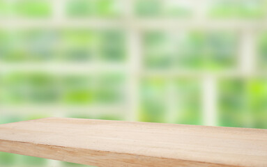 Wooden table top on blur window glass and abstract green color from garden with city view on morning background. For product display mounting