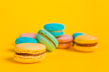 Sweet almond colorful unicorn pink blue yellow green macaron or macaroon dessert cake isolated on trendy yellow modern fashion background. French sweet cookie. Minimal food bakery concept Copy space