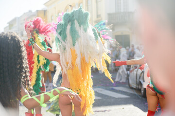 Dancers wearing colorful feathers costumes gathered for a parade. Back view blurry defocused...