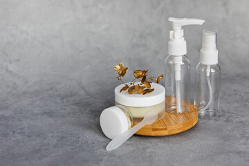 A jar of face cream on a wooden stand on a gray background. Set for skin and body care beauty products banner format