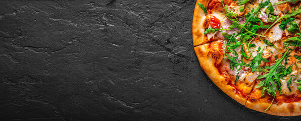 Pizza with chicken, bacon, cheese, tomato and arugula. Italian pizza on Dark grey black slate...