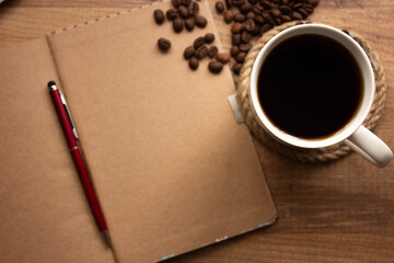cup of coffee, coffee beans and notebook on wooden table in workplace, selective focus. For to do list background, top view. copy space for your text