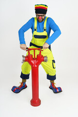 The clown fireman turns the valve on the fire hydrant.
