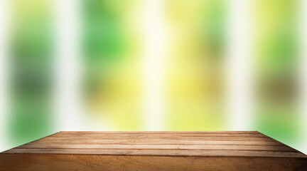 Wooden table top on blur window glass and abstract green color from garden with city view on morning background. For product display mounting