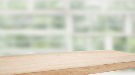 Wooden table top on blur window glass and abstract green color from garden with city view on...
