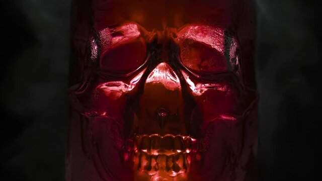 Blood Red Glass Skull. Bright, rich blood-red glass vessel in the form of the skull, from which are evaporation and slow down the edges on a black background