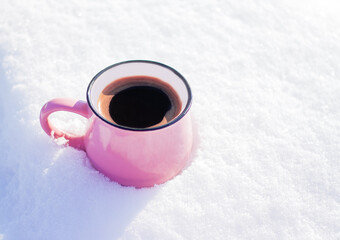 pink cup with hot coffee stands on the snow outdoor