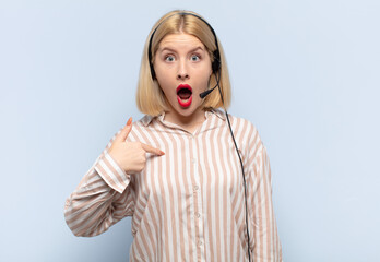 blonde woman looking shocked and surprised with mouth wide open, pointing to self
