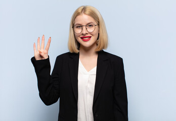 blonde woman smiling and looking friendly, showing number four or fourth with hand forward,...