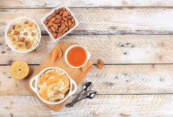 Useful breakfast with ingredients, flat lay, rice pudding with bananas, honey, tangerines and almonds on a sunny table. Healthy and natural food concept, lifestyle, food for children,